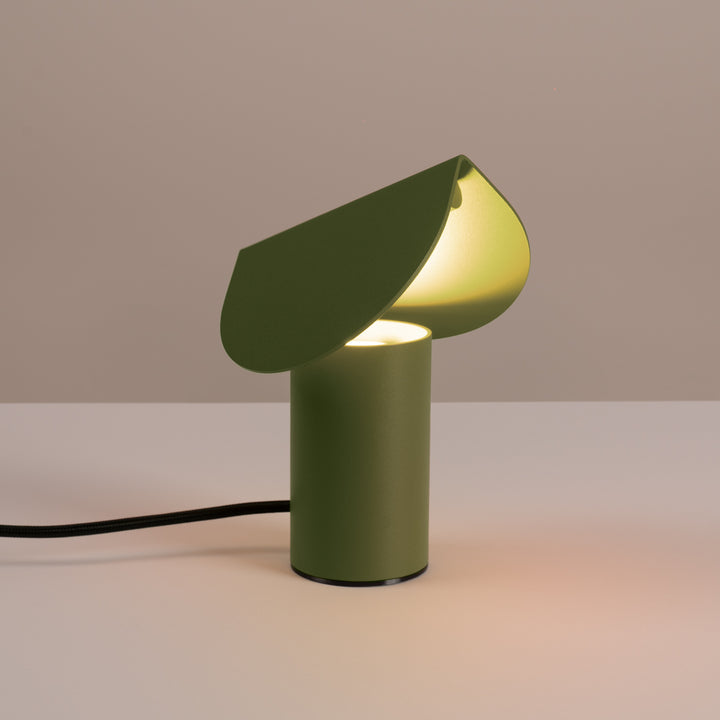 Lampe à poser BISCUIT vert olive allumée, sur une table