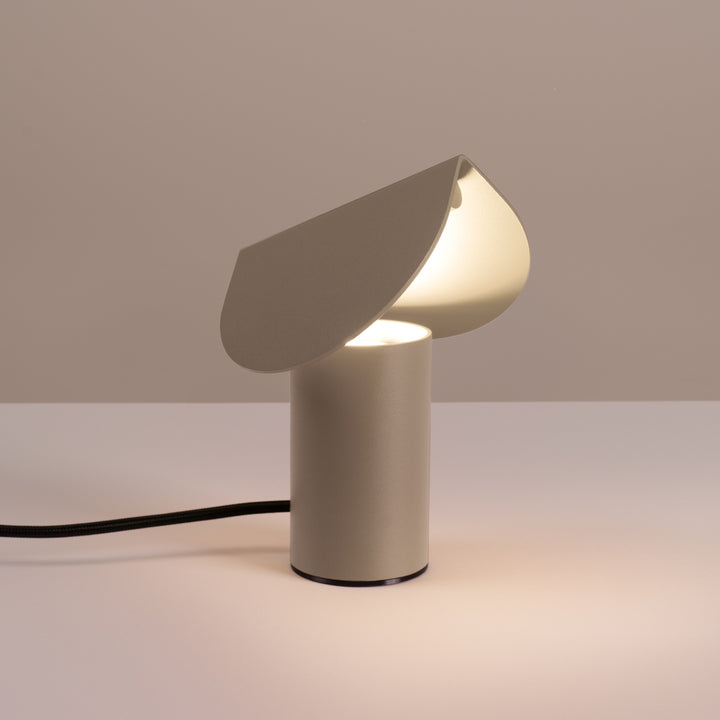 Lampe à poser BISCUIT taupe allumée, sur une table