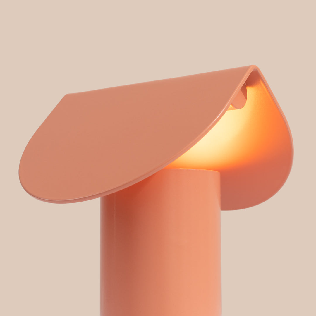 Lampe à poser BISCUIT pêche allumée, vue de trois quarts