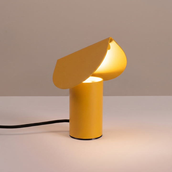 Lampe à poser BISCUIT jaune allumée, sur une table