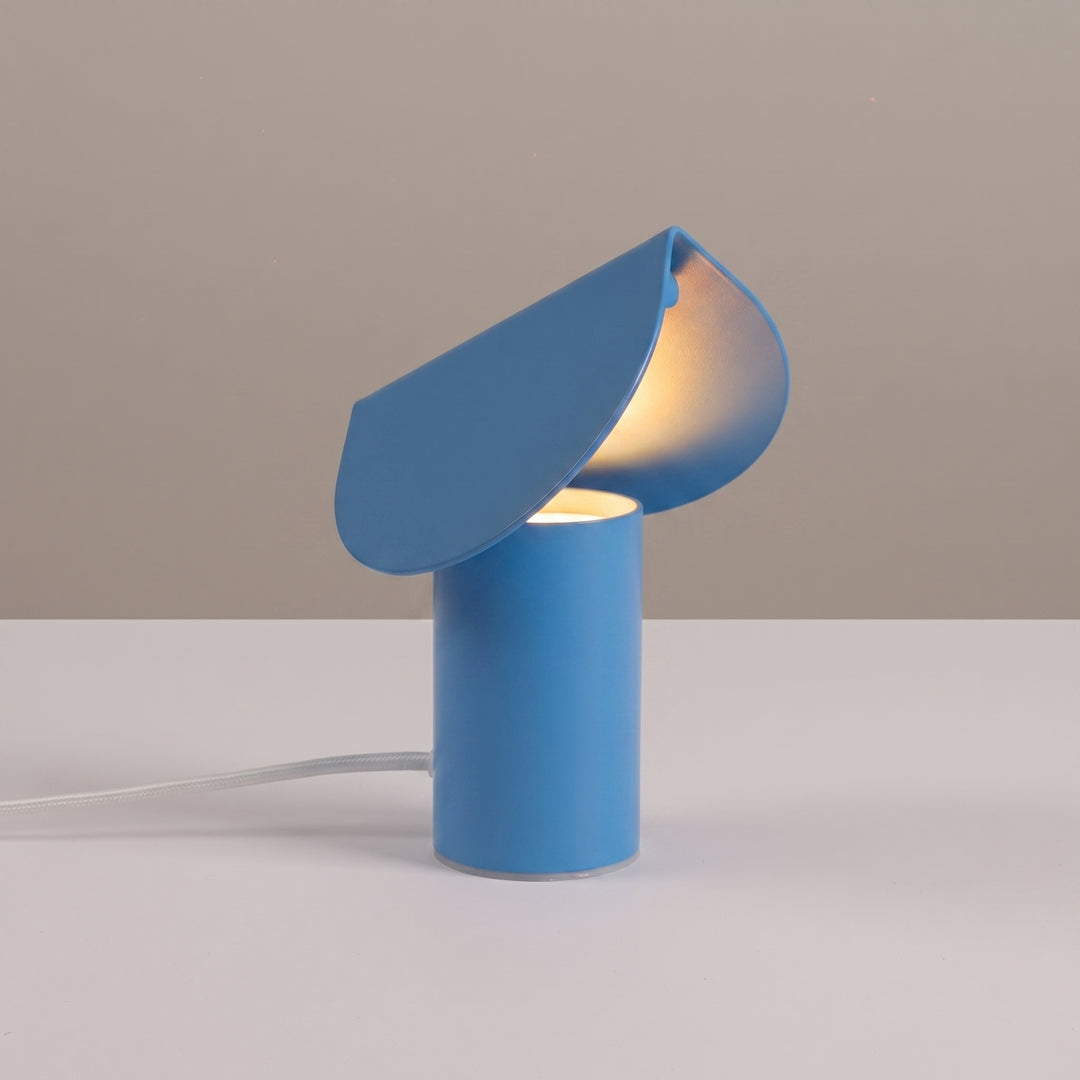Lampe à poser BISCUIT bleu clair allumée, sur une table