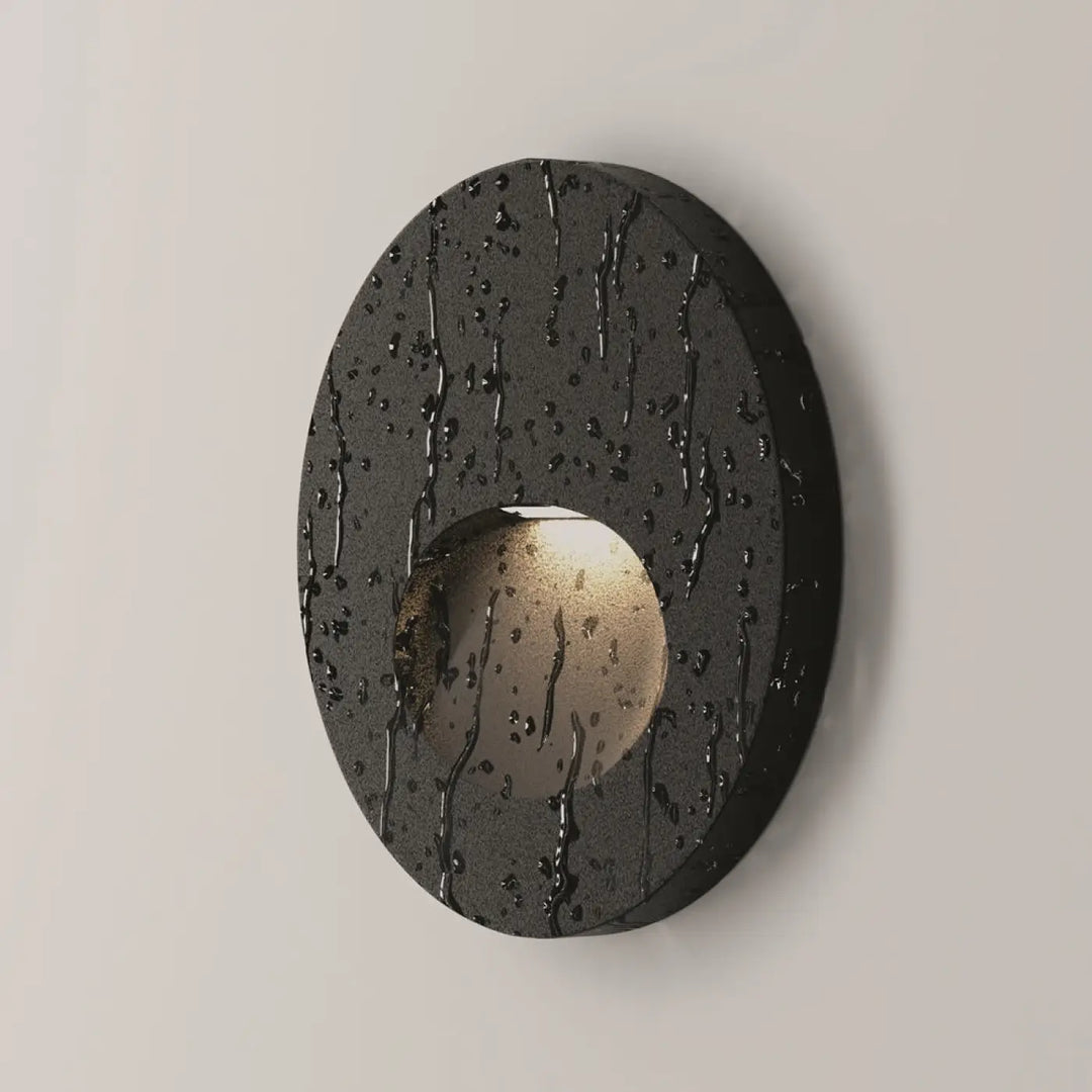 Applique encastrée noire ovale avec surface texturée effet gouttes de pluie et lumière douce intérieure visible