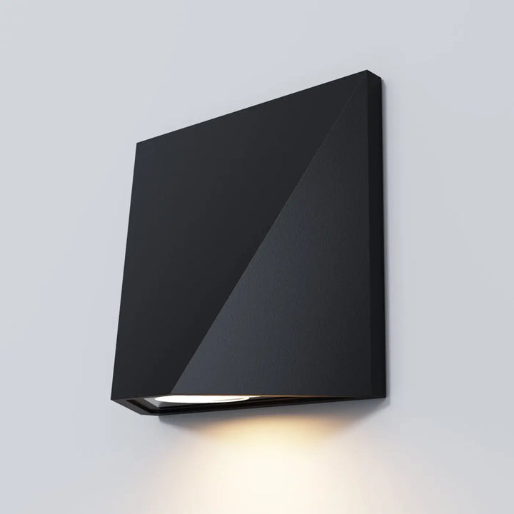 Applique extérieure beekman en aluminium noir avec design géométrique angulaire, émettant lumière chaude long d’un escalier