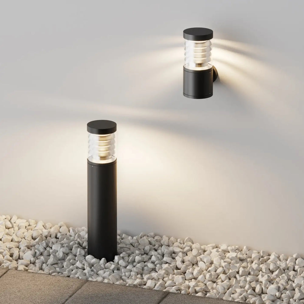 Applique extérieure en acier noir avec verre strié cylindrique et diffuseur givré émettant une lumière chaude