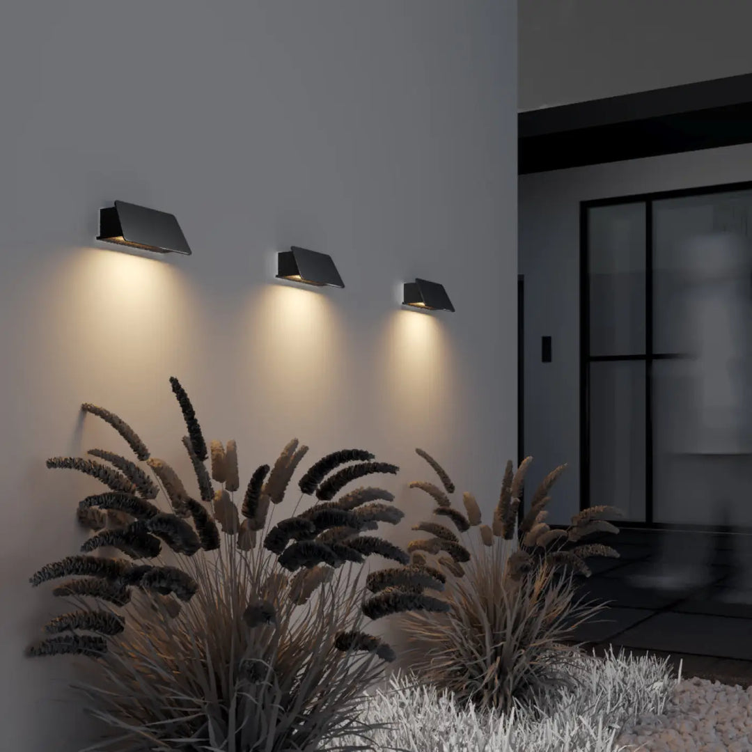 Applique extérieure led trupp en acier noir avec trois appliques murales angulaires près d’une porte
