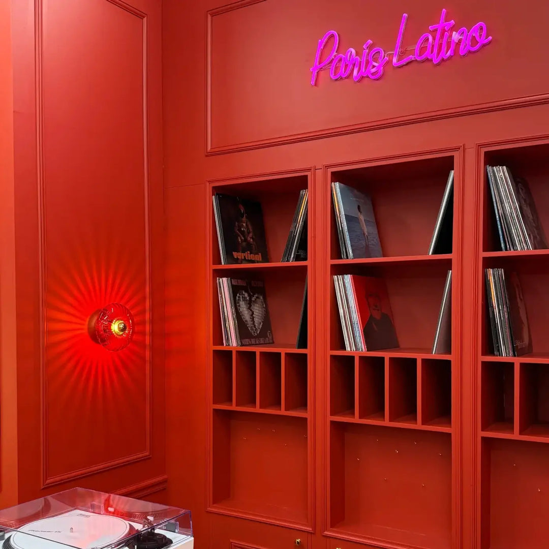 Applique grace en verre soufflé rouge vibrant avec neon paris latino au-dessus d’etageres integrées de vinyles