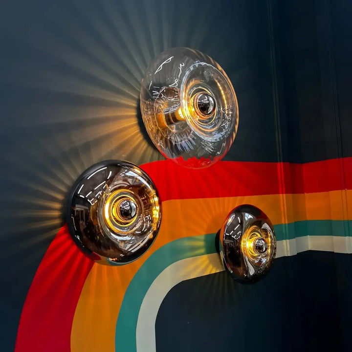 Trois appliques murales grace en verre soufflé avec un design facetté transparent et lumière dorée chaleureuse