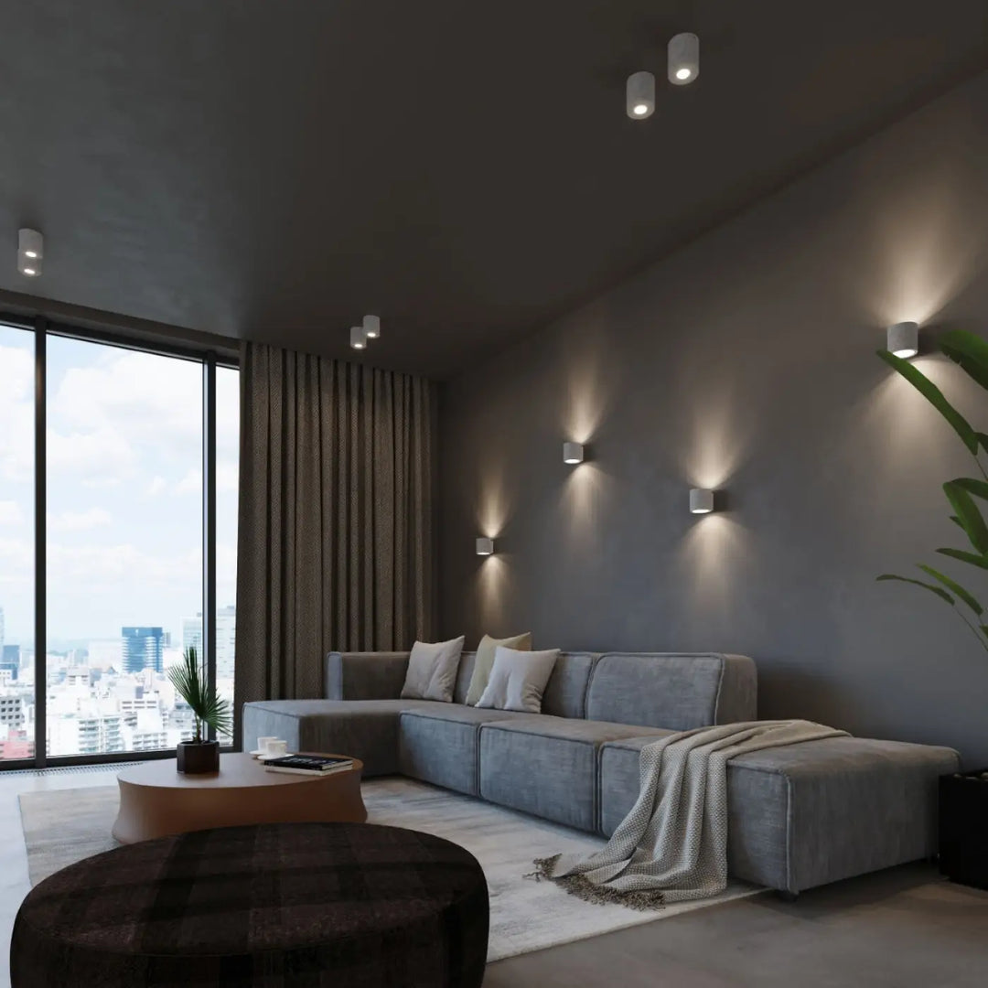 Sectionnel gris avec coussins moelleux et plaid texturé sur laccoudoir accompagné de kinkiet orbis beton