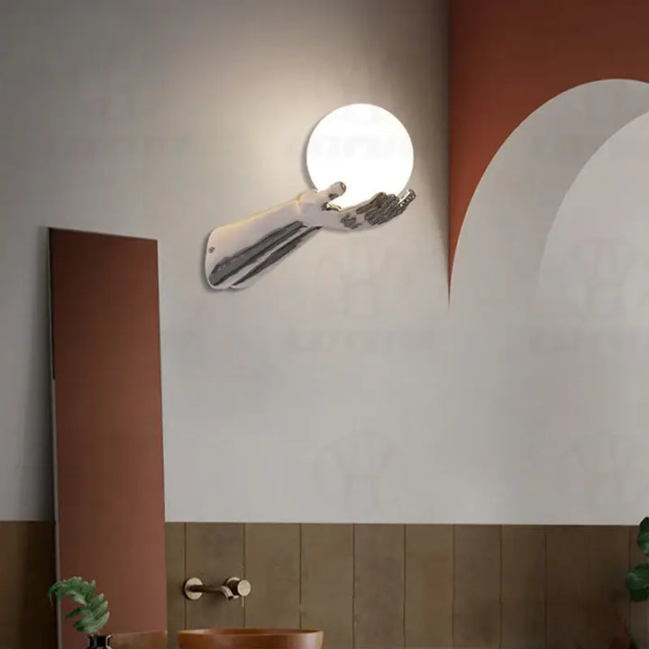 Applique murale avec brand tendu tenant une boule blanche

