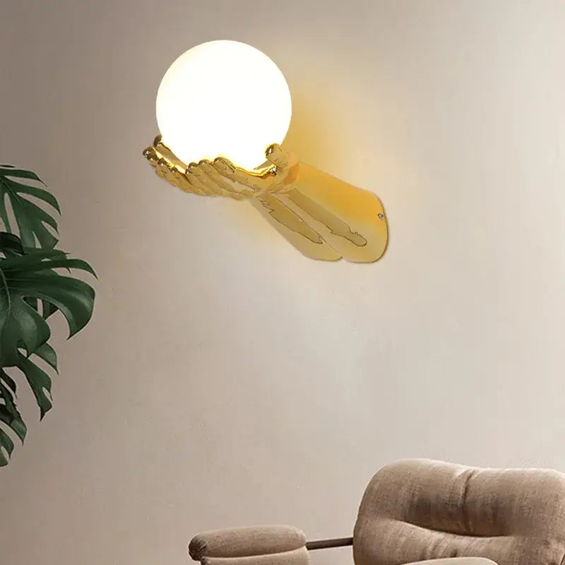 Applique murale avec brand tendu tenant une boule blanche

