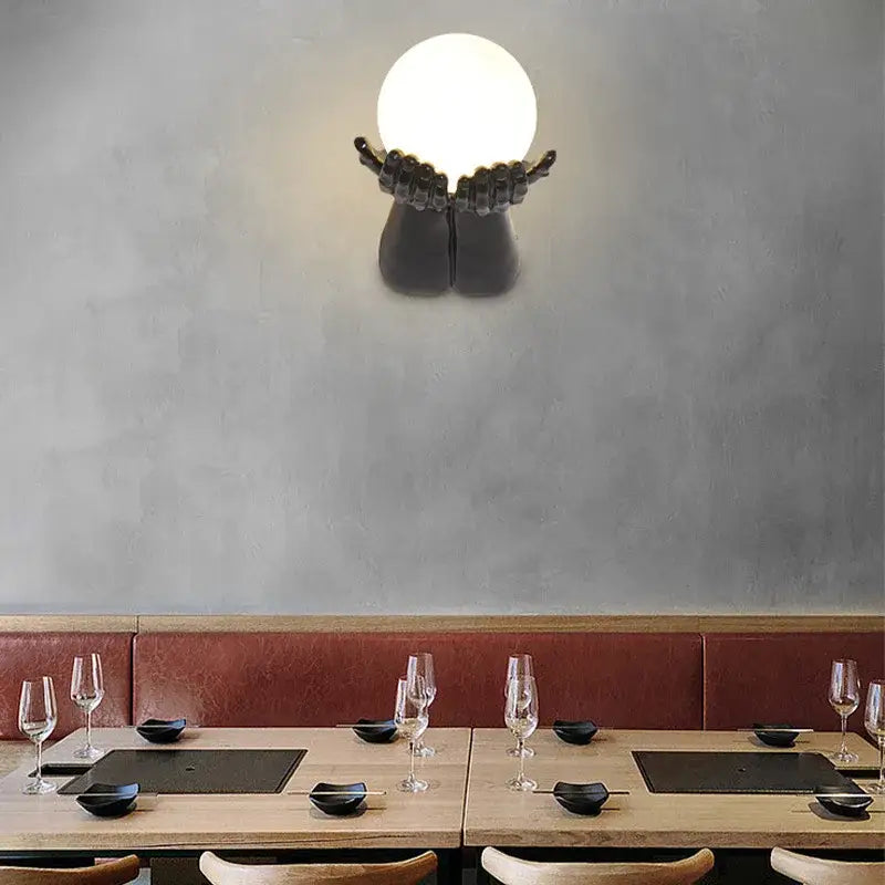 Applique murale avec brand tendu tenant une boule blanche

