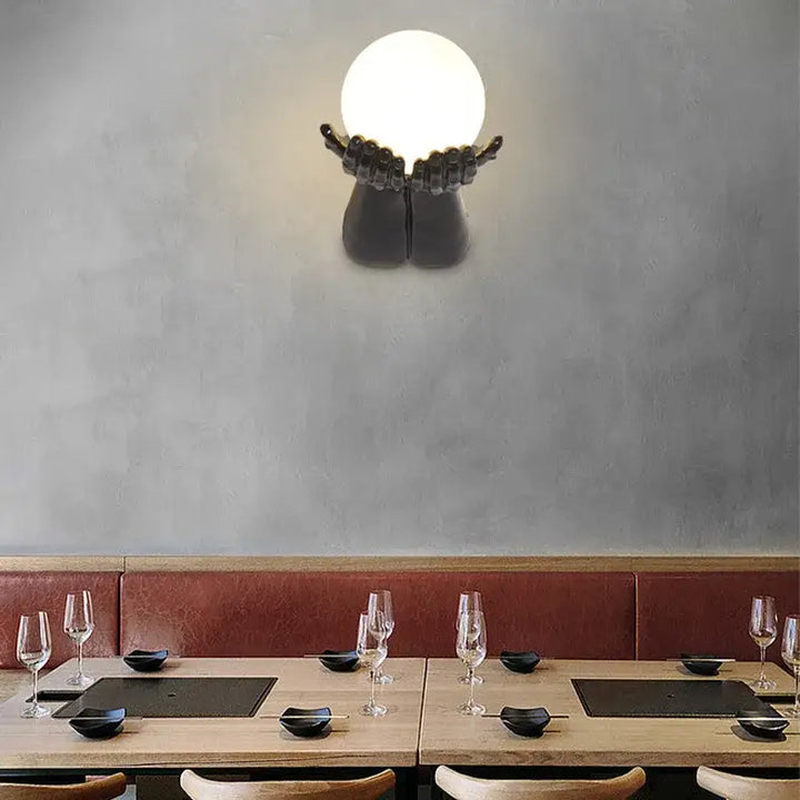 Applique murale avec brand tendu tenant une boule blanche

