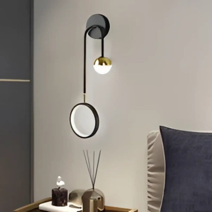Applique murale orialis en noir et laiton avec bras courbé et anneau suspendu décoratif et ampoule chaude