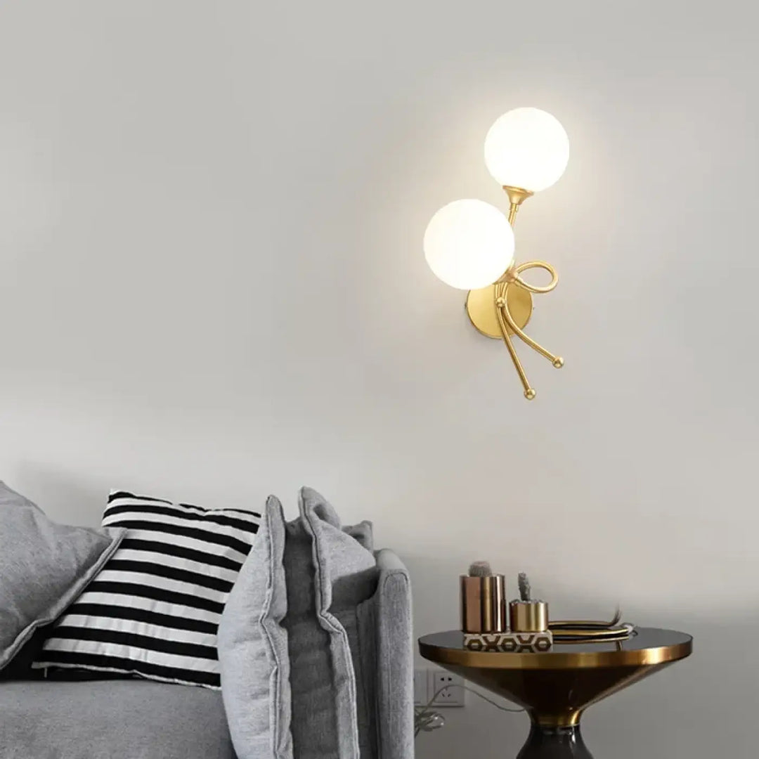 Applique murale zylo en métal doré avec deux globes en verre dépoli et bras décoratif en forme de nœud