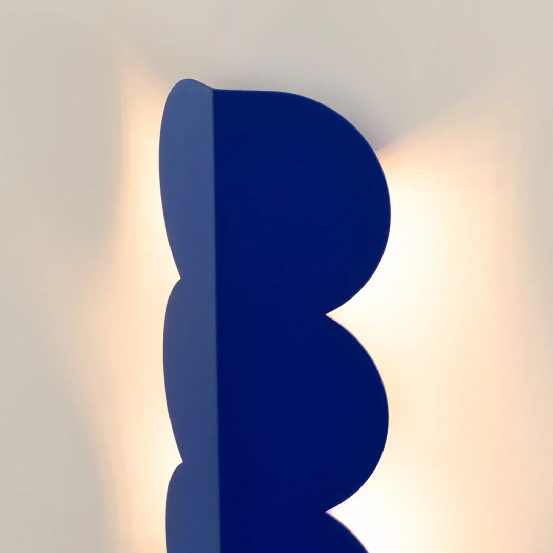 Applique murale biscuit outremer en cobalt bleu avec forme ondulée caractéristique compose d’une lampe élégante