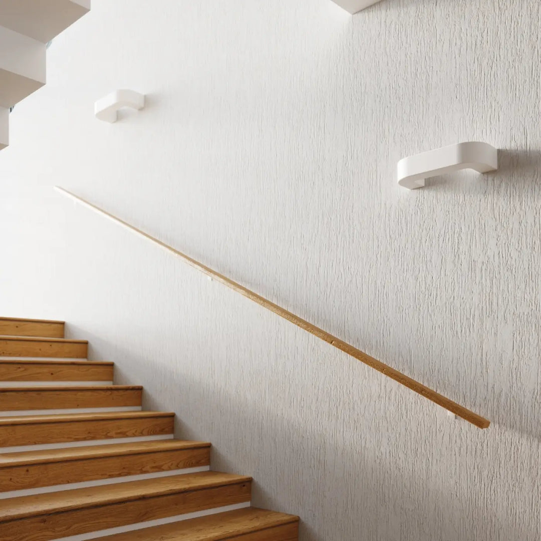 Applique murale moderne en céramique magnet avec belle lumière installée sur mur blanc texturé près d’une rampe en bois clair