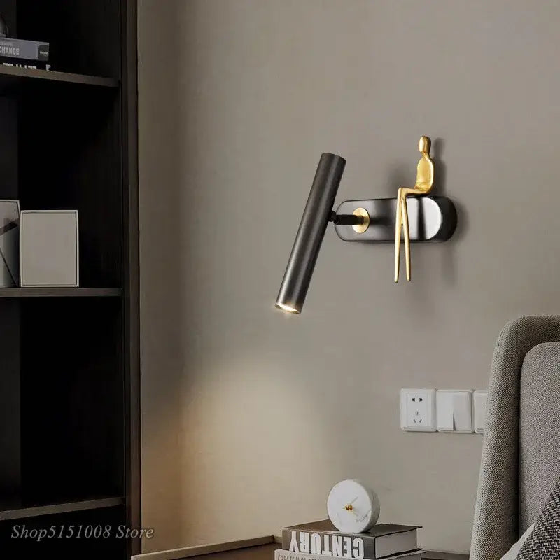 Applique murale LED noir avec un bonhomme doré assis

