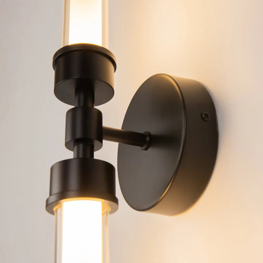 Applique murale led noire en métal avec deux tubes longs verticaux en verre diffusant une lumière chaude