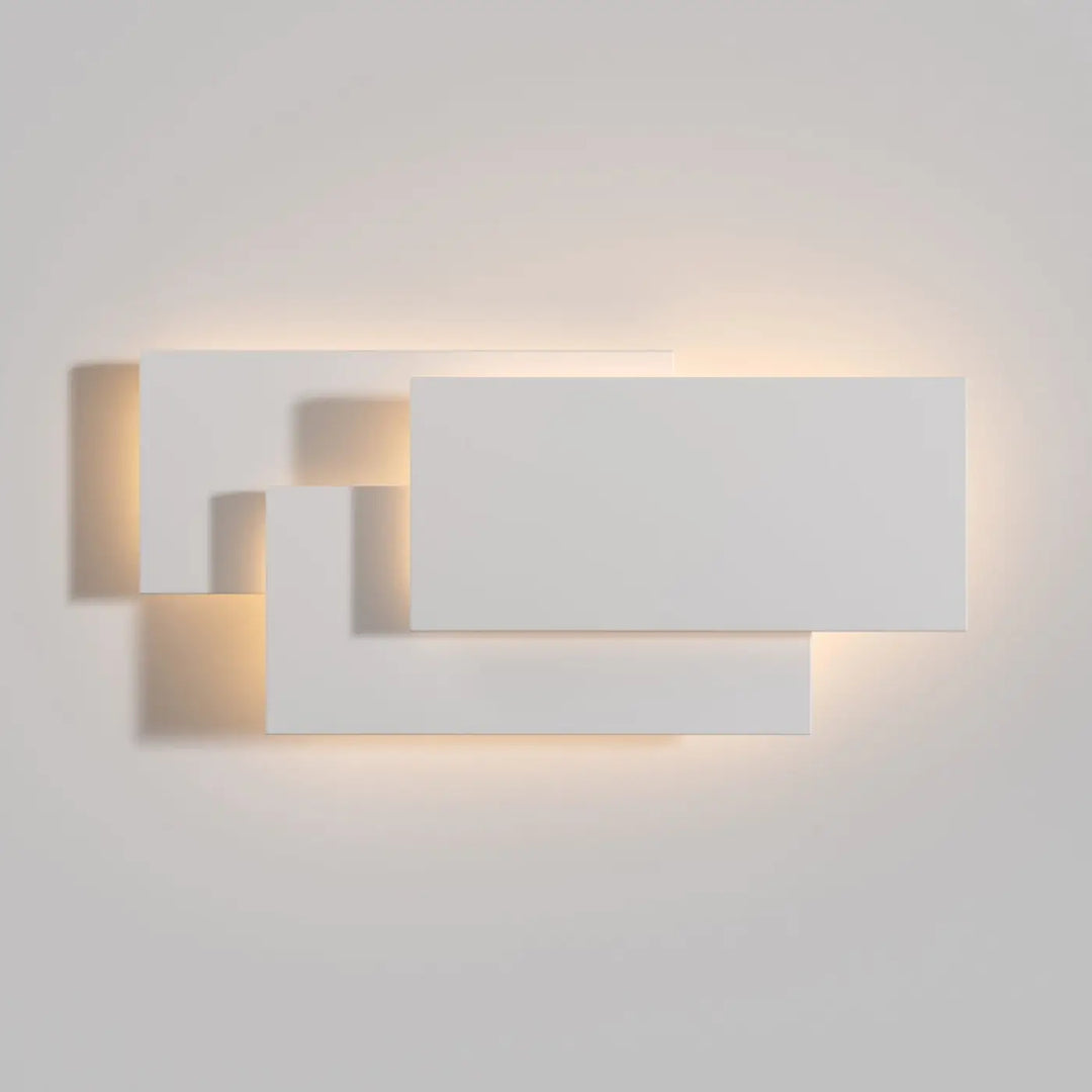 Applique murale led en acier blanc moderne avec panneaux géométriques superposés émettant une lumière ambiante