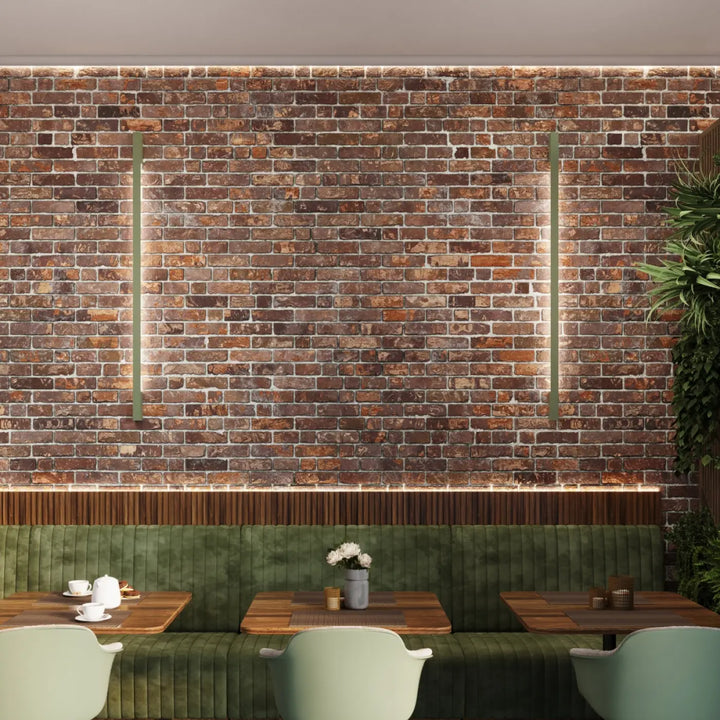 L’applique murale lahti 50 led 4000k vert olive éclaire élégamment des banquettes en velours vert sur un mur en brique rustique