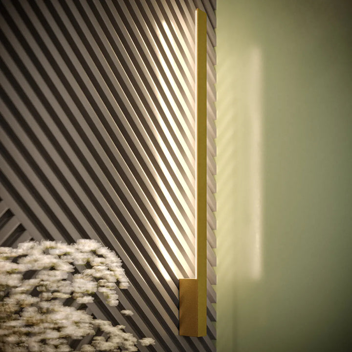 Applique murale lahti l 4000k doré avec boîtier étroit et module led diffuse une lumière chaude sur fond texturé rayé