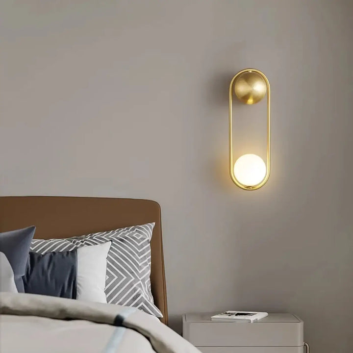 Applique murale isaih en métal doré avec cadre ovale et accents sphériques diffusant une lumière blanche élégante