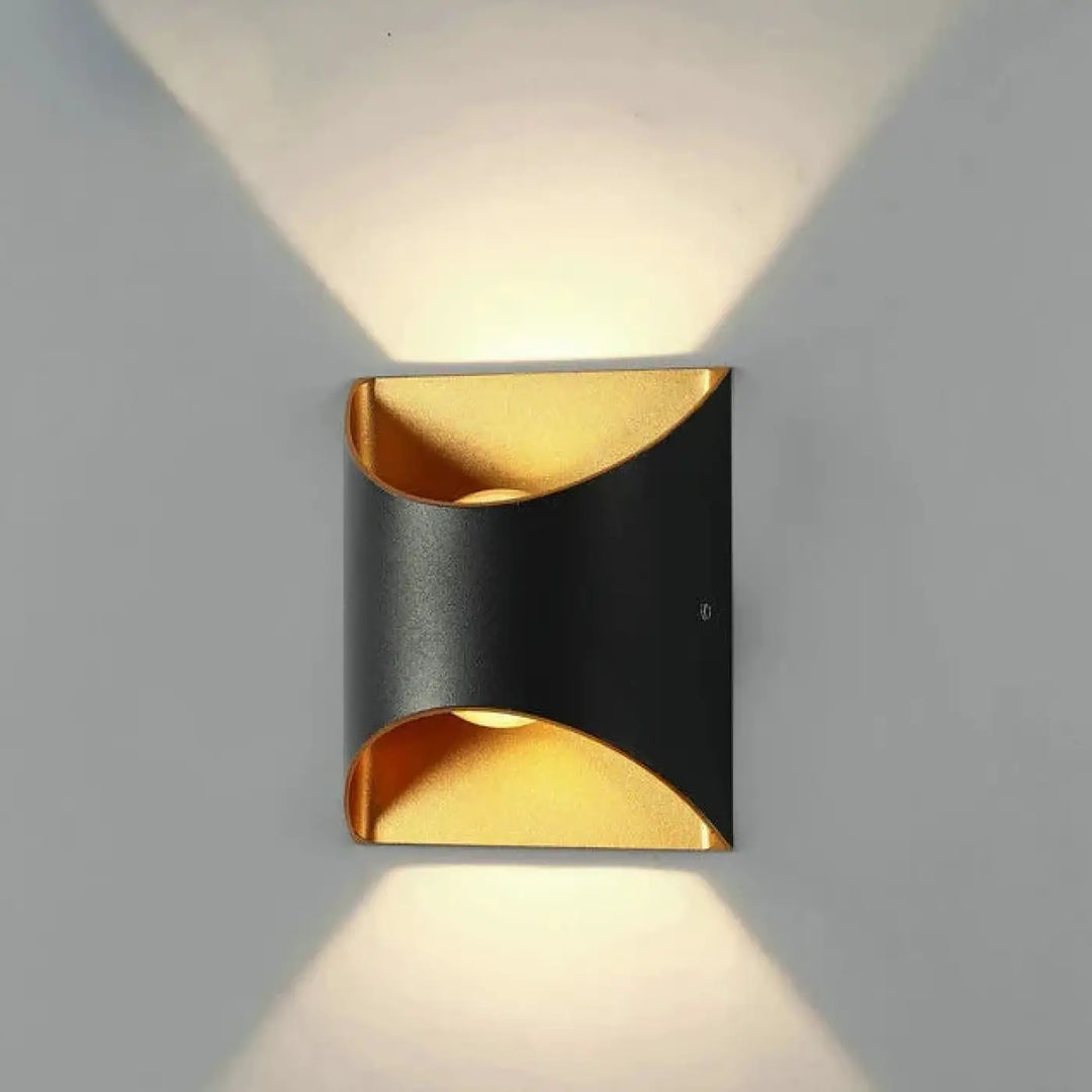 Applique murale moderne noire et dorée avec design courbé diffusant une lumière chaude dans deux directions