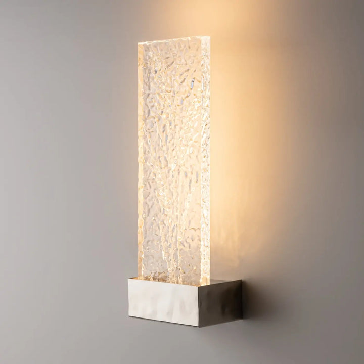 Applique murale ornate avec panneau de verre translucide texturé diffusant une lumière chaude sur base métallique sleek
