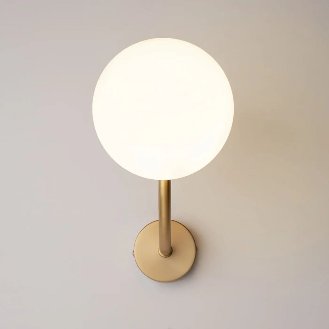 Applique murale rendez vous avec globe en verre blanc givré et bras doré minimaliste en laiton élégant
