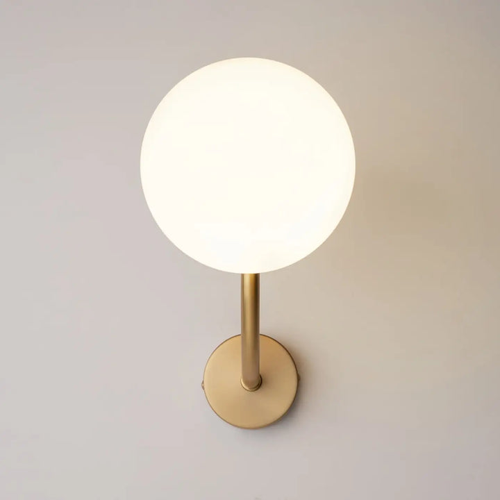 Applique murale rendez vous avec globe en verre blanc givré et bras doré minimaliste en laiton élégant