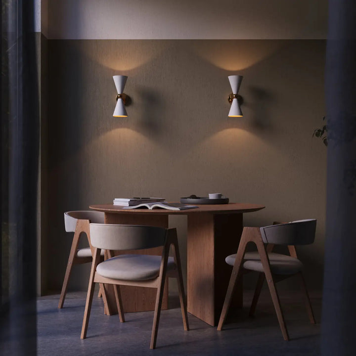 Table à manger moderne en bois avec plateau rond et design minimaliste entourée de chaises assorties pour applique murale vesper