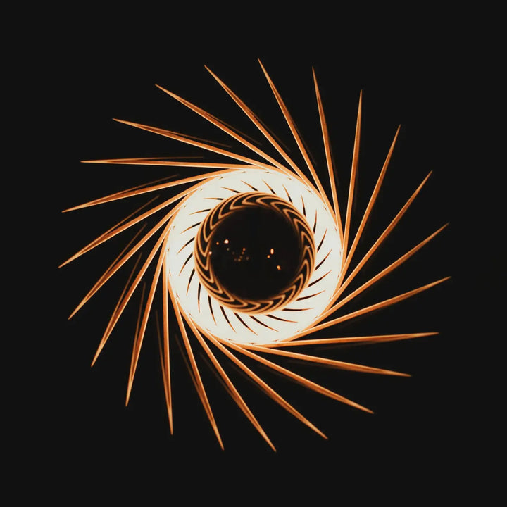 L’applique murale pianumayö en bois fsc présente des traînées lumineuses dorées en spirale partant d’un centre blanc