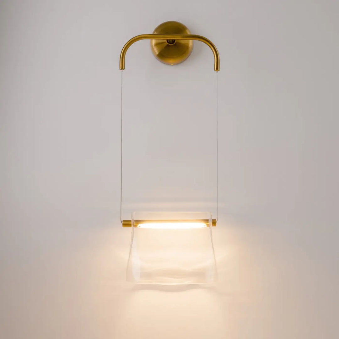 Applique suspendue cabaret en métal finition laiton avec diffuseur en verre transparent émettant une lumière chaude