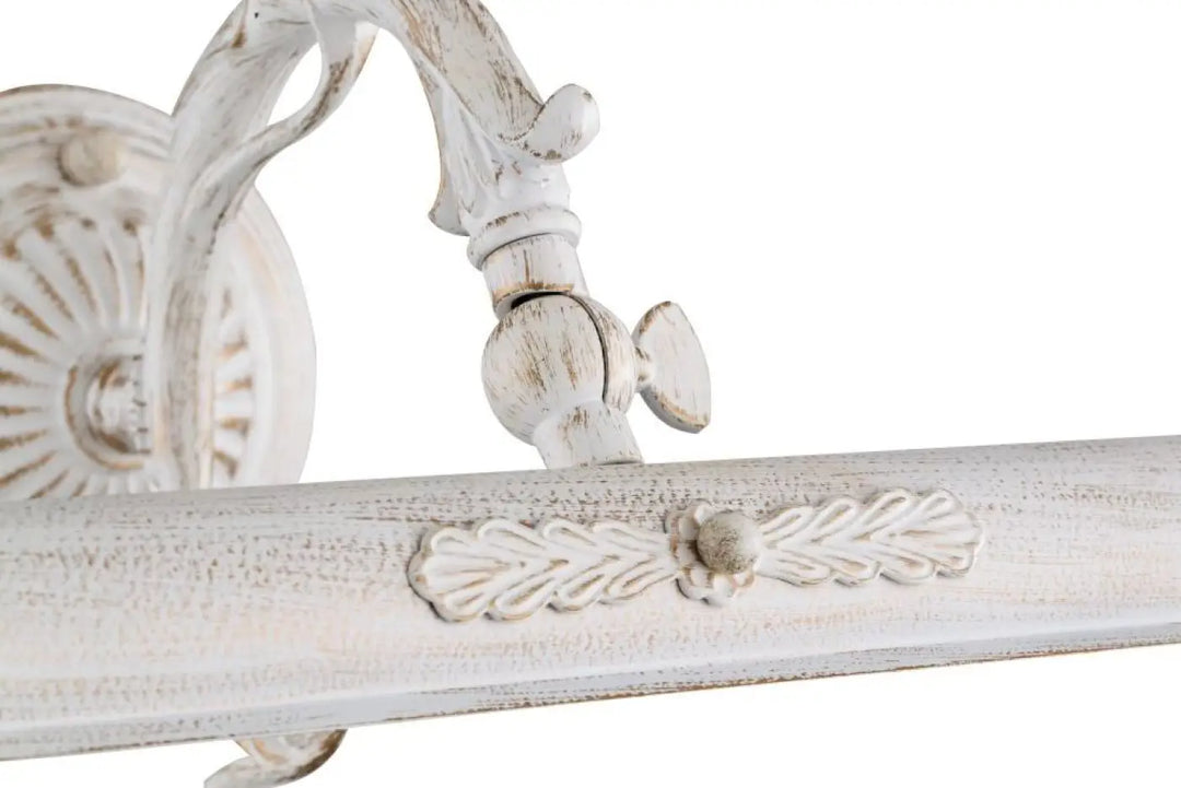 Applique murale picasso en bois blanc vieilli avec bras déporté ornée de feuilles et motifs pour ampoules e14 au-dessus d’un meuble