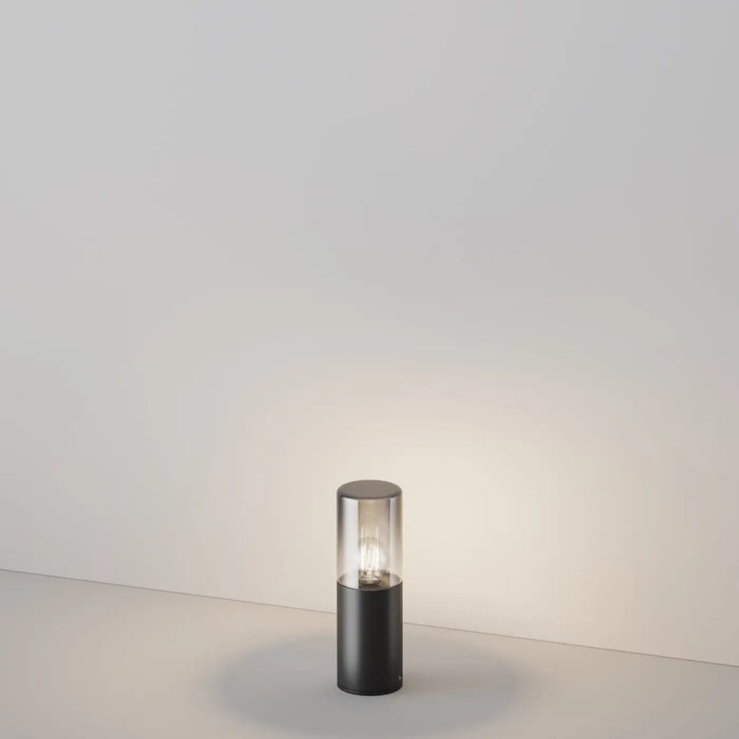 Borne extérieure amas en aluminium graphite avec lampe cylindrique noire et verre teinté clair abritant une ampoule visible