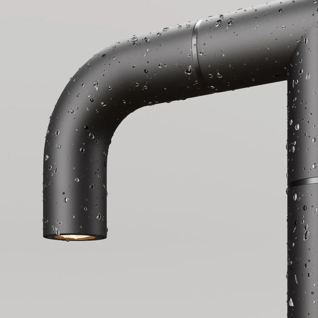 Borne extérieure led en aluminium noir à finition mate industrielle avec gouttes d eau sur sa surface courbée