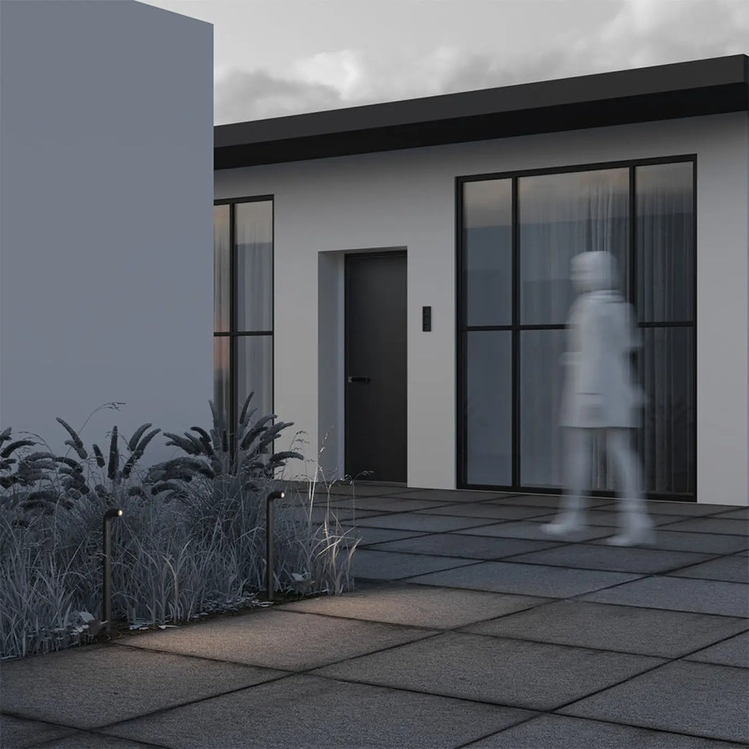 Borne extérieure led sleek cubique en aluminium noir devant maison moderne avec porte grise et fenêtres noires