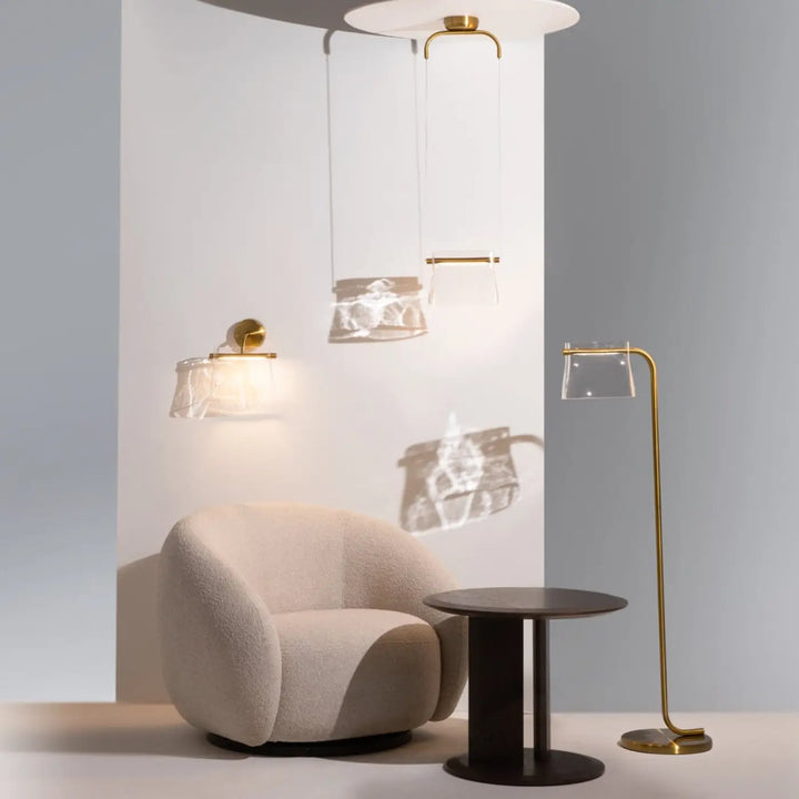 Fauteuil beige en tissu texturé doux avec contours arrondis associé au lampadaire cabaret art déco en verre transparent