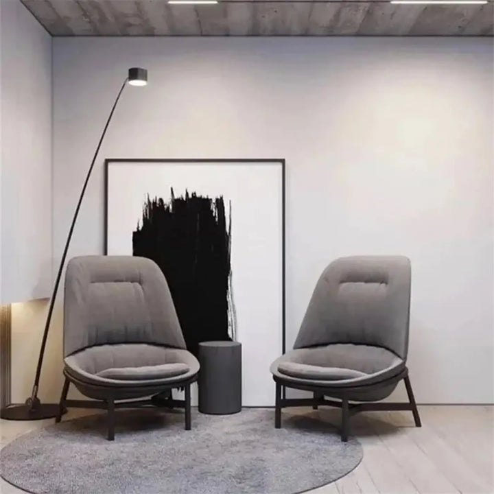 Deux fauteuils modernes en tissu gris avec pieds en bois foncé dans une pièce minimaliste avec un lampadaire design fer type nyris