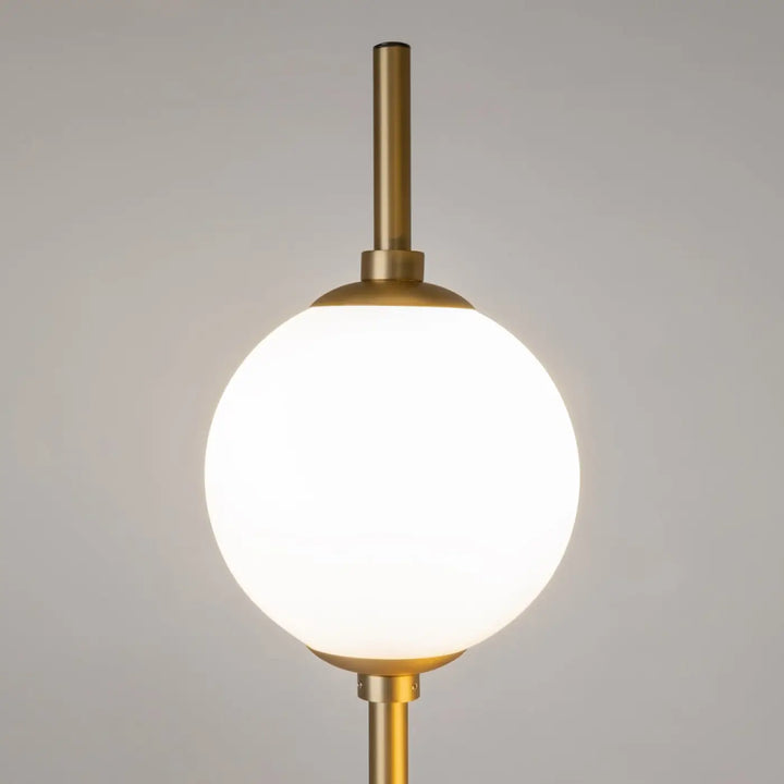 Lampadaire sixth sense en laiton avec globe sphérique en verre blanc, design élégant et lumineux pour intérieur contemporain