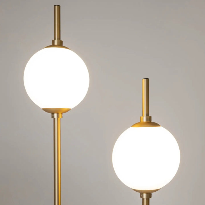 Lampadaire sixth sense avec deux globes en verre dépoli sur tiges métalliques finition or moderne et élégant