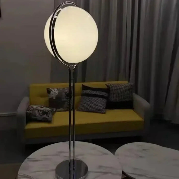 Lampadaire isandy chrome avec ampoule sphérique blanche entourée danneau métallique moderne et élégant
