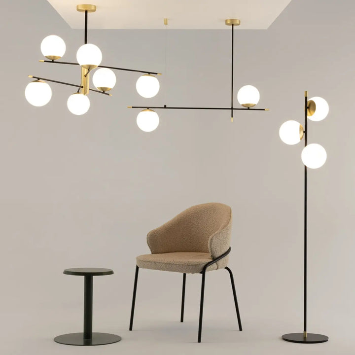 Lampadaire nostalgia trois globes en acier noir avec globes en verre opalin et chaise beige au cadre metalique noir