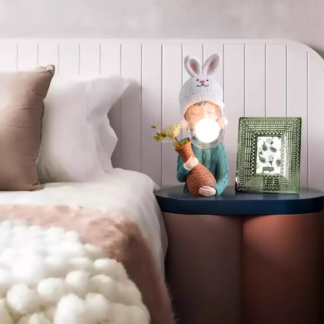 Lampe de chevet tiloux avec figurine lapin portant bonnet lapin et pull, tenant un globe lumineux en vase tissé