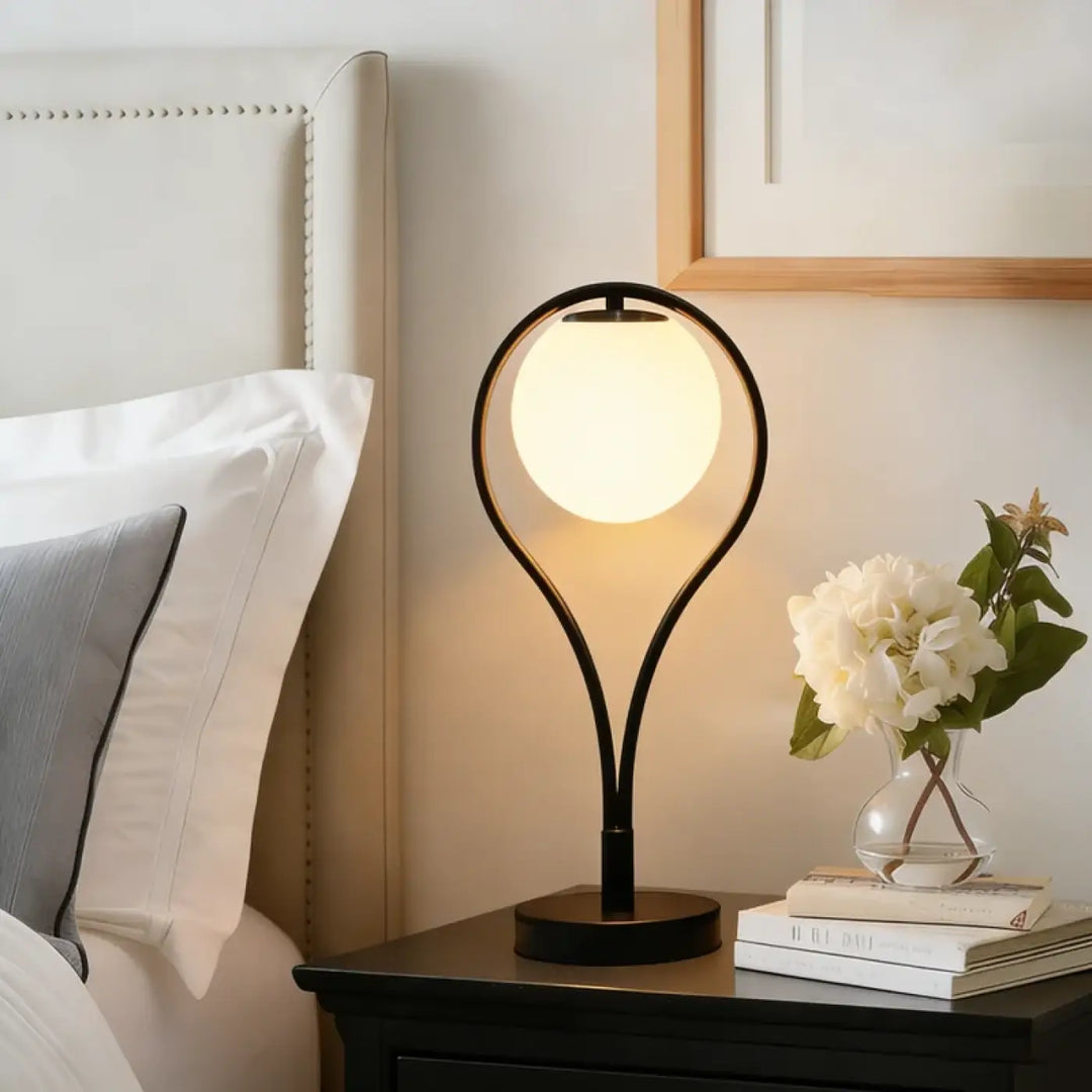 Lampe de table canila en métal noir avec globe en verre lumineux offrant un halo lumineux pour un chevet design
