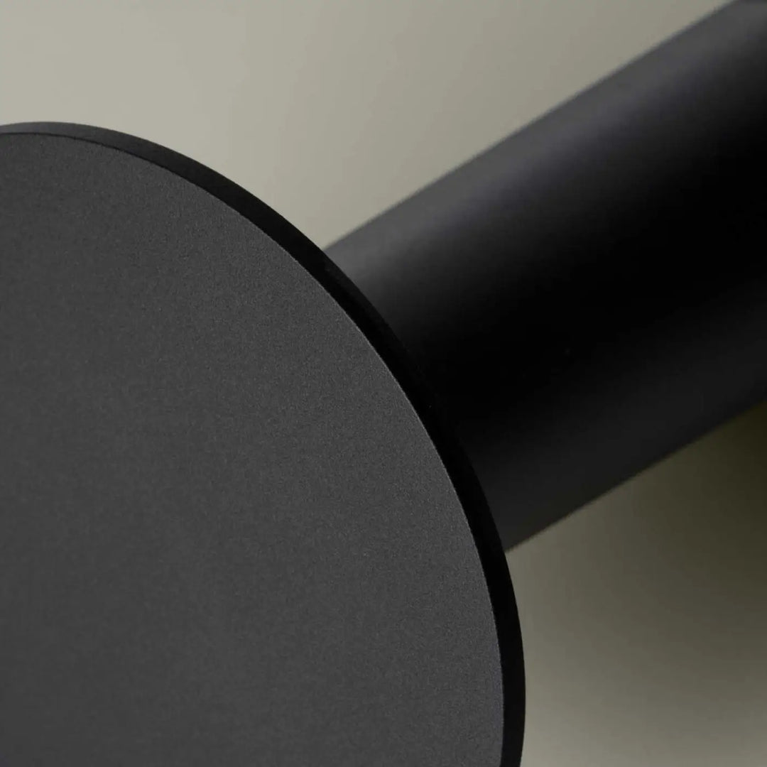 Matte black cylindrical table leg with smooth modern finish of lampe cocktail featuring variation tactile and tête orientable