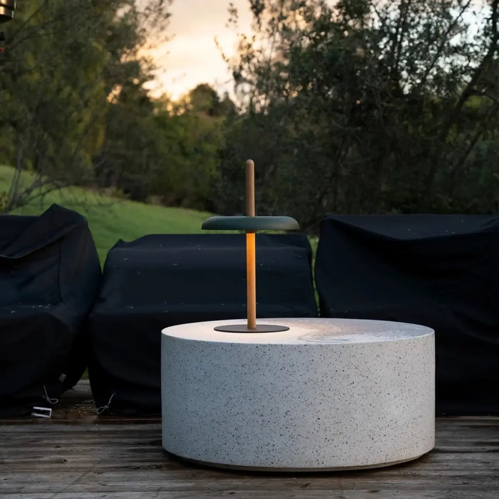 Lampe de chevet nivél avec base en béton blanc éclaté, poteau central en bois et plateau circulaire vert foncé en acier thermolaqué