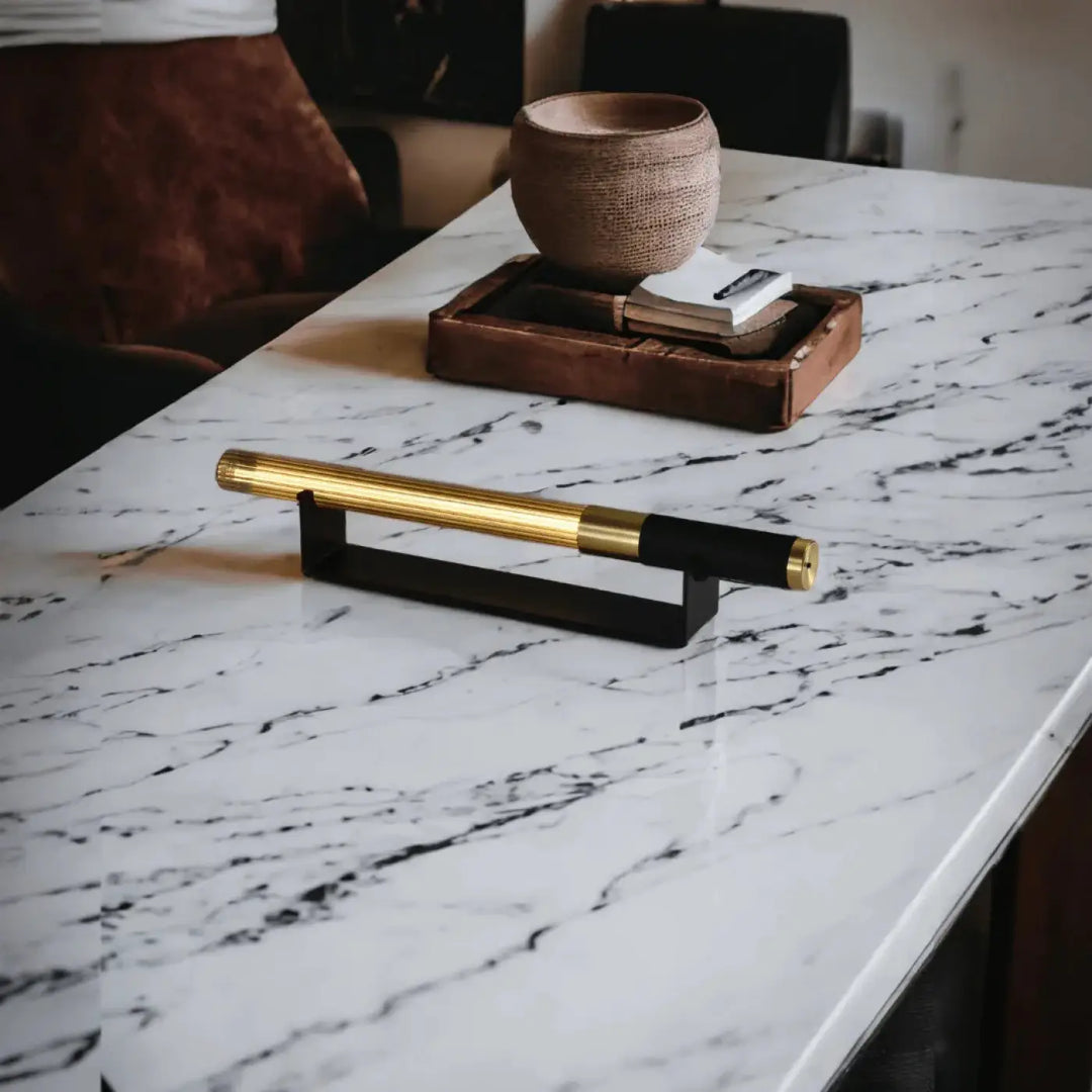 Lampe de chevet hélios avec objet lumineux cylindrique noir et or au design moderne sur un support minimaliste