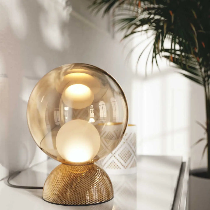 Lampe de chevet charm avec globe compact ambré et sphère lumineuse cachée sur base métal doré texturée pour poser charm