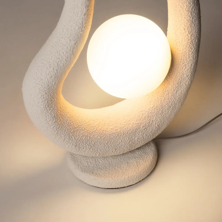 Lampe de chevet blanche avec socle sculptural texturé et bulbe sphérique lisse comme objet d’art